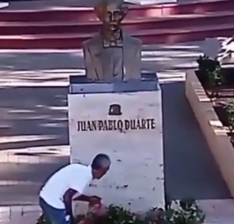Hombre se desmonta de su pasola para limpiar y decorar estatua de Juan Pablo Duarte
